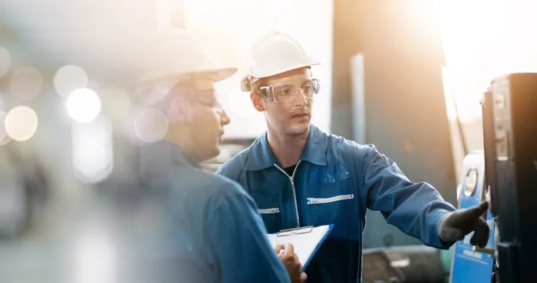 Factory deskless workers checking information on industrial digital signage screen in workshop
