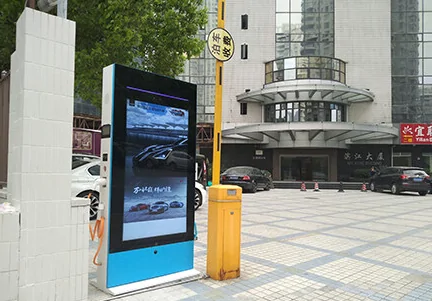 Outdoor EV charging station integrated with vertical digital signage advertising display