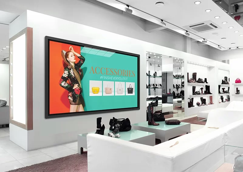Wall mounted retail digital signage inside fashion boutique, showing accessories promotional ads