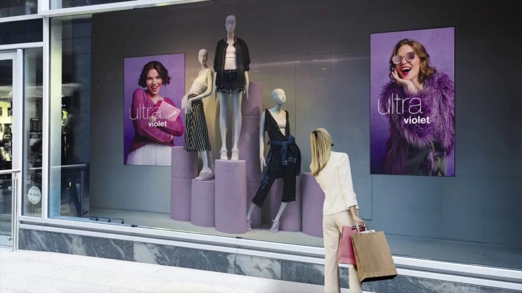 Digital signage screens on retail shop window, shopper viewing fashion promotional content