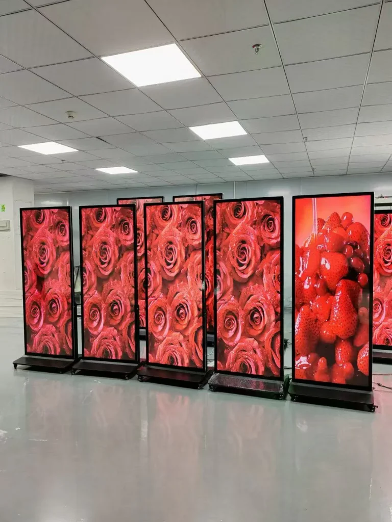 Batch vertical LCD poster digital signage showing rose and fruit promotional images inside manufacturing workshop