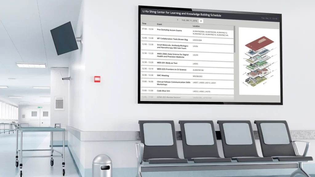 Wall mounted digital directory screen showing building schedule and floor map in hospital waiting area
